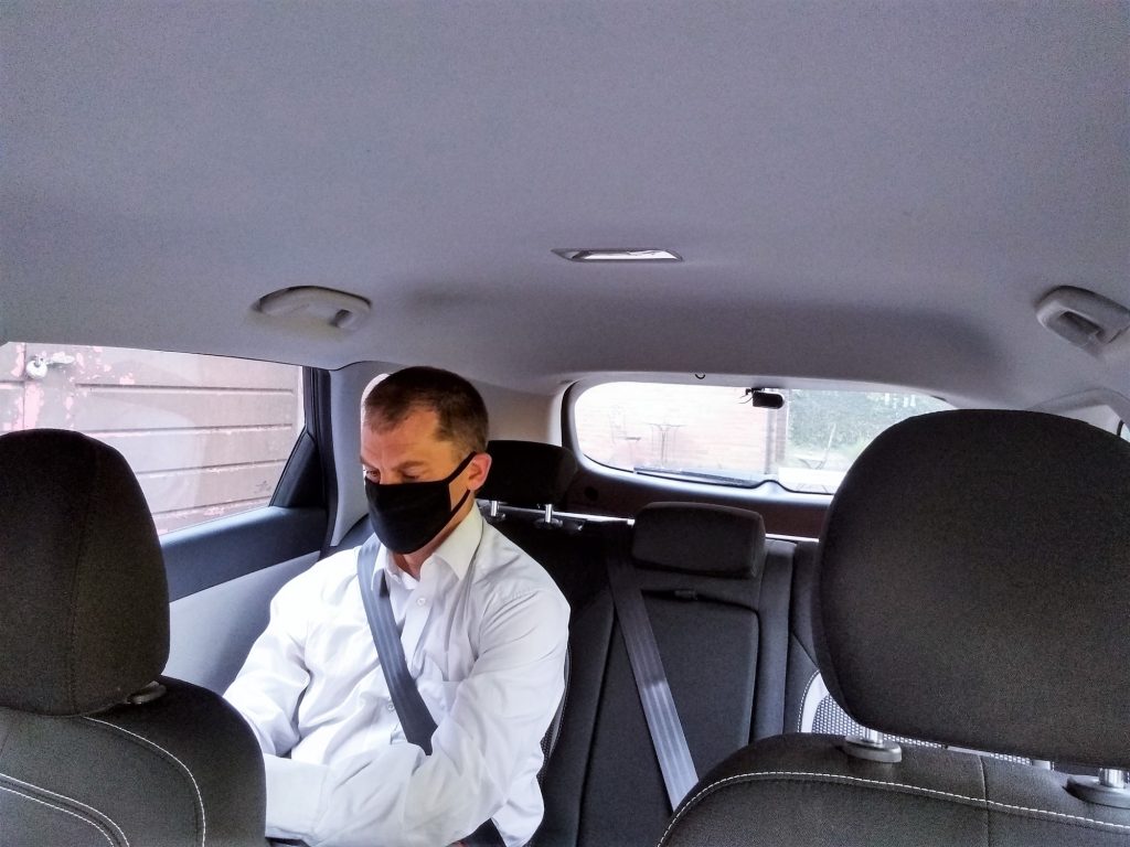 Man in back of taxi wearing a mask
